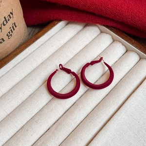 Detail of red flocked circular hoop earrings on beige velvet jewelry box in cozy autumn setting