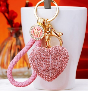 Macro shot of pink rhinestone heart keychain with gold finish and woven strap detail