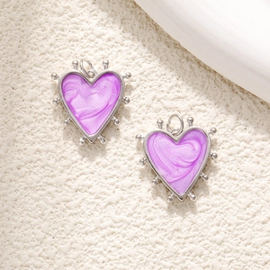 Detail of two purple heart pendants with silver beaded frames and enamel centers