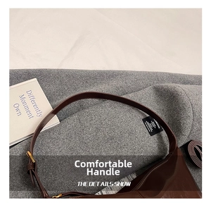 Detail of dark brown leather tote bag with adjustable strap on tweed fabric