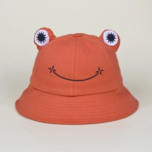 Detail of brick red frog bucket hat featuring 3D eyes and black embroidered smile