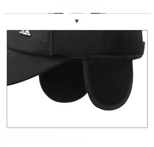 Detail of winter baseball cap featuring earflaps and Sportbest metal logo on black fabric