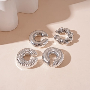 Macro detail of silver C-shaped ear cuffs set featuring smooth and twisted metal textures