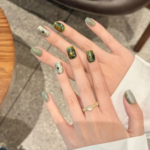 Emerald green cat-eye press-on nails with golden eye relief and marble patterns