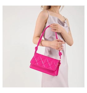 Detail of rose pink crossbody bag with geometric quilting and decorative knotted strap