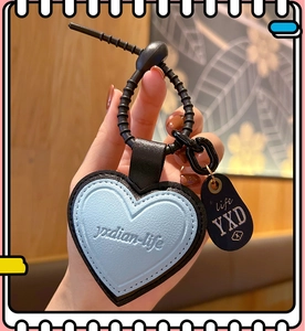 Detail of blue leather heart pendant keychain with black spring ring held in hand
