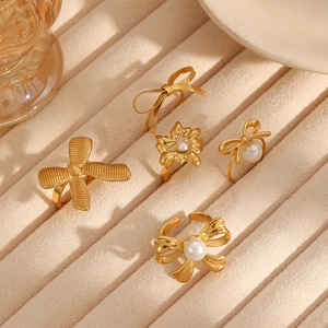 Golden bow and pearl rings set in titanium steel for women, displayed on velvet
