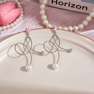 Détail de la boucle d'oreille cœur rose avec perle sur un plateau en céramique