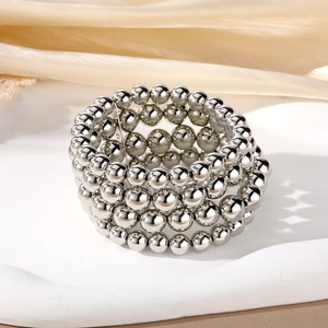 Silver multi-layer beaded bracelet set with mirror finish on white tray and silk background