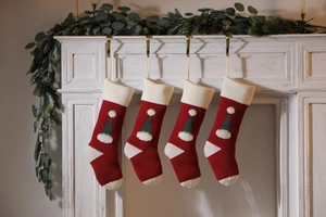Close-up of four knitted Christmas stockings with 3D hats hanging on a white mantel