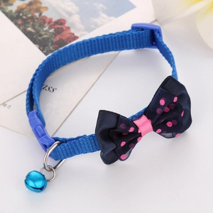 Close-up of blue nylon pet collar with pink polka dot bow and matching bell accessory