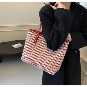 Side view of red houndstooth tote bag with leather trim and metal rivets on model