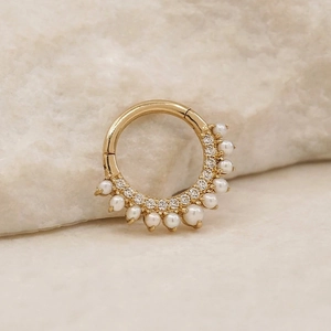 Detail of a gold S925 silver nose ring featuring small pearls and clear zircon stones