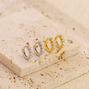 Detailed close-up of gold and silver geometric earrings set with sparkling zircons