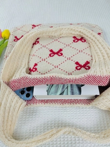 Detailed top view of a cream knit tote bag with red bows showing large storage capacity