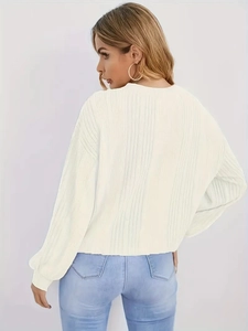 Gros plan sur un pull en maille blanche avec manches bouffantes et détails perlés