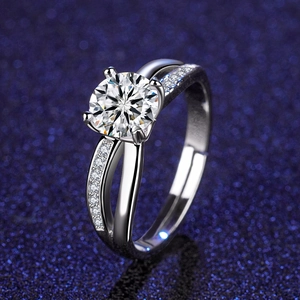 Macro shot of a four-prong moissanite ring with split shank and pavé accents on blue background