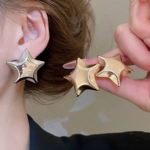 Macro shot of polished gold and silver star stud earrings with a glossy metallic finish