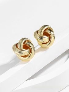 Detail of gold twisted knot earrings with fine horizontal textures on white paper display