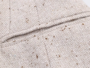Gros plan sur la texture du tweed beige et les coutures précises du bord de la poche