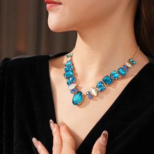 Close-up of gold necklace with blue geometric gemstones worn by a female model