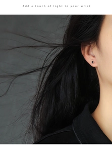 Close-up of minimalist square black zircon stud earring worn on model's ear