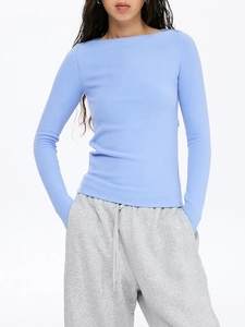 Haut de yoga bleu clair à manches longues ajusté avec un jogging gris en studio propre