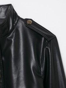 Detail der schwarzen Kunstlederjacke mit Schulterklappen und goldenem Metallknopf