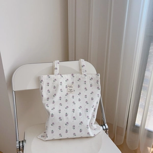 Detail of light purple floral cotton tote bag with vintage cloth label on a chair