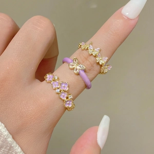 Detail of three-piece ring set with purple enamel flower and zircon bow accents