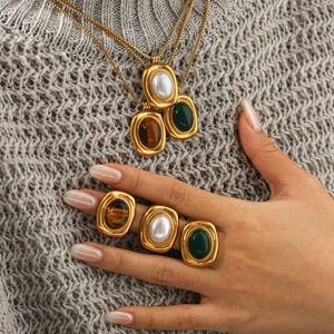 Detail of French vintage gold-toned jewelry set with tiger eye, pearl and green stone