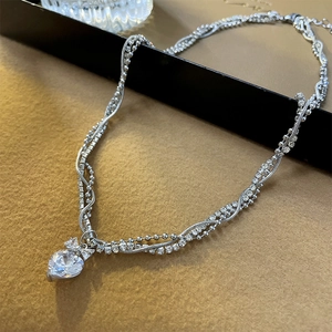 Detail of silver multi-layer necklace with heart zircon pendant and bow ornament