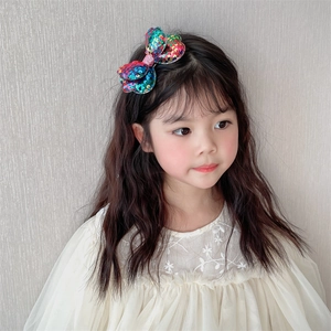 Detail of colorful sequined double-layer bow hair clip on a young girl's hair