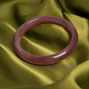 Close-up of lavender cat's eye stone bracelet on olive green silk fabric background