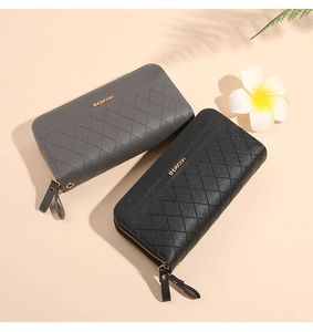Detail showing grey and black quilted long wallets with wrist straps and zippers