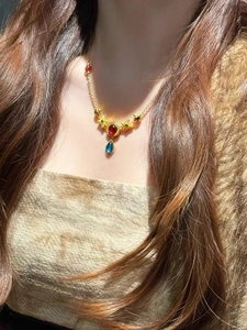 Close-up of Bohemian layered necklace with red round stone and blue teardrop pendant
