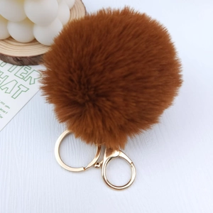 Detailed view of a soft brown plush pompom keychain with a golden metal lobster clasp