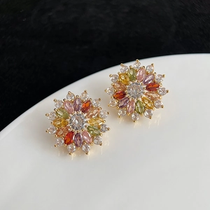 Gros plan de boucles d'oreilles fleur plaquées or avec zircons colorés sur un plateau