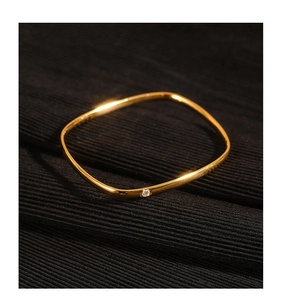 Close-up of golden wavy titanium steel ring featuring a sparkling zircon on dark fabric