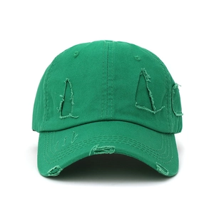 Close-up of distressed green cotton baseball cap showing ripped details and vintage texture