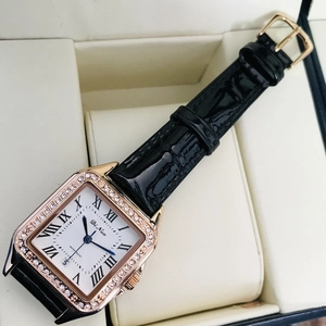 Detail view of square rose gold watch with diamond bezel and black patent leather strap
