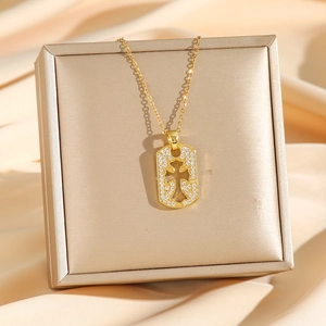 Collana con ciondolo a croce dorata e zirconi cubici esposta su una scatola per gioielli