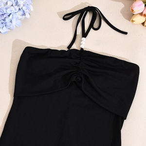Détail de la robe dos nu noire en maille côtelée avec trois perles blanches sur l'encolure