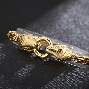 Close-up of golden dual snake head bracelet featuring detailed scale textures and square links
