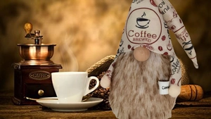 Close-up of a coffee gnome doll with brew pattern hat and a small white mug