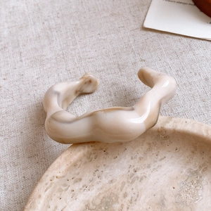 Close-up of marble pattern resin bangle with wavy irregular design on linen background