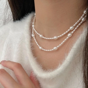 Close-up of elegant double-layered irregular white pearl necklace on model's neck
