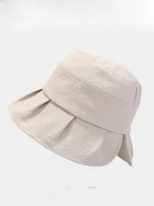 Detail of beige bucket hat featuring pleated brim and textured fabric weave texture