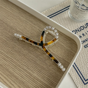 Detail of tortoise shell hair claw with pearl trim on a wooden tray setting