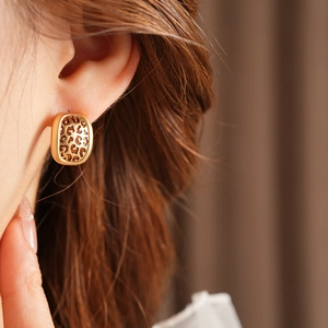 Mannequin portant des boucles d'oreilles dorées avec motif léopard en forme de carré